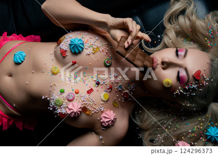 Woman with body art and colorful candy-themed decoration enjoying chocolate 124296373