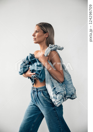 Fashionable woman poses with denim apparel in stylish outfit against a minimalist background 124296709