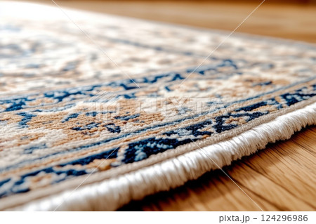 Close up of a fringed edge on a handmade persian rug with intricate design, resting on a polished wooden floor 124296986