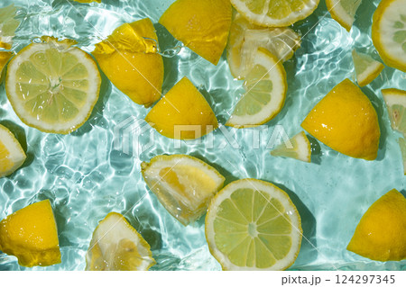 Refreshing turquoise citrus background with floating yellow lemon pieces 124297345