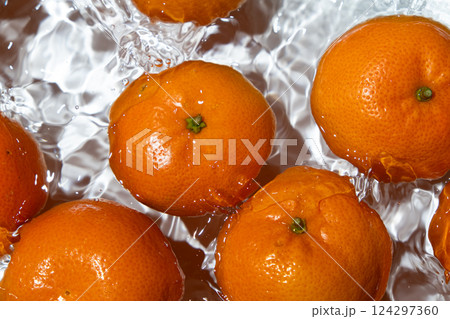 Fresh tangerines splashing into clear water top view 124297360
