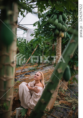 Woman enjoying a moment of tranquility among papaya trees in a greenhouse Woman enjoying a moment of tranquility among papaya trees in a greenhouse 124297422