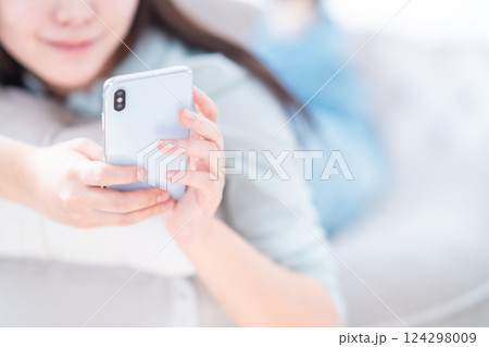 寝転んでリラックスしながらスマホを見る若い女性　顔無し 124298009