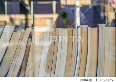 Row of neatly arranged old books behind glass window in historic bookstore. Glimpse into literary history , vintage charm. Many books and reflection in glass, background, copy space 124298575