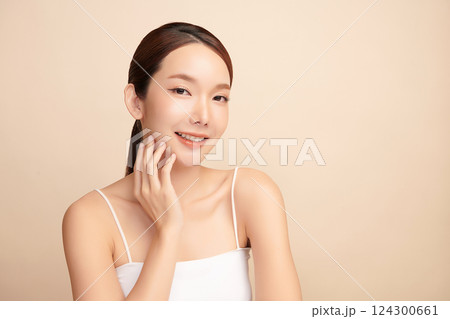 A beautiful young Asian woman with clean, fresh skin against a beige background. Skincare, facial treatment, cosmetology, beauty, and spa. An elegant portrait of an Asian woman. A beautiful young Asian woman with clean, fresh skin against a beige background. Skincare, facial treatment, cosmetology, beauty, and spa. An elegant portrait of an Asian woman. 124300661