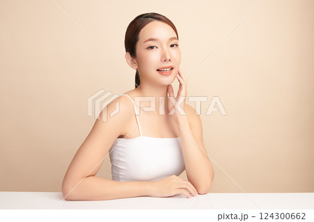 A beautiful young Asian woman with clean, fresh skin against a beige background. Skincare, facial treatment, cosmetology, beauty, and spa. An elegant portrait of an Asian woman. A beautiful young Asian woman with clean, fresh skin against a beige background. Skincare, facial treatment, cosmetology, beauty, and spa. An elegant portrait of an Asian woman. 124300662