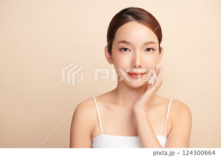 A beautiful young Asian woman with clean, fresh skin against a beige background. Skincare, facial treatment, cosmetology, beauty, and spa. An elegant portrait of an Asian woman. 124300664
