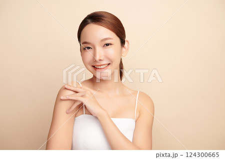 A beautiful young Asian woman with clean, fresh skin against a beige background. Skincare, facial treatment, cosmetology, beauty, and spa. An elegant portrait of an Asian woman. 124300665
