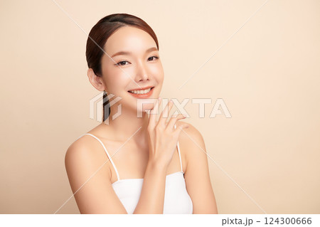A beautiful young Asian woman with clean, fresh skin against a beige background. Skincare, facial treatment, cosmetology, beauty, and spa. An elegant portrait of an Asian woman. 124300666