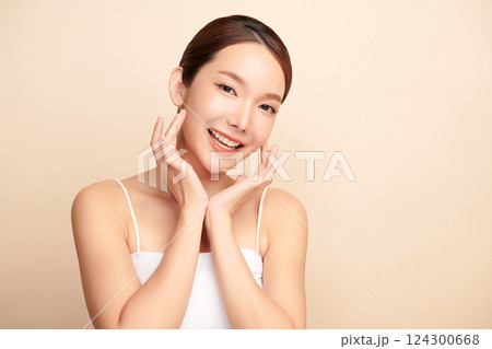 A beautiful young Asian woman with clean, fresh skin against a beige background. Skincare, facial treatment, cosmetology, beauty, and spa. An elegant portrait of an Asian woman. 124300668