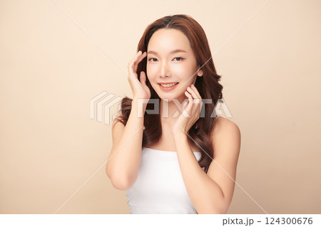 A beautiful young Asian woman with clean, fresh skin against a beige background. Skincare, facial treatment, cosmetology, beauty, and spa. An elegant portrait of an Asian woman. 124300676