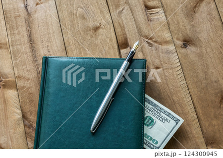 Diary, pen and part of a bill on a wooden surface 124300945