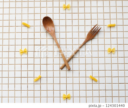 time to eat pasta. wooden plate with fork and spoon in form of clock hands. pasta on plate. time to eat pasta. wooden plate with fork and spoon in form of clock hands. pasta on plate. 124301440
