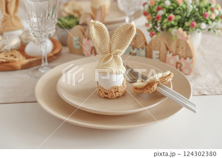 Festive Easter table setting with Easter bunny made from egg and knitted ears. Easter celebration concept 124302380
