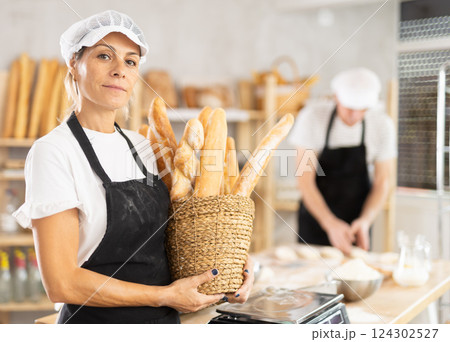Elderly woman with basket of baguettes in bakery Elderly woman with basket of baguettes in bakery 124302527