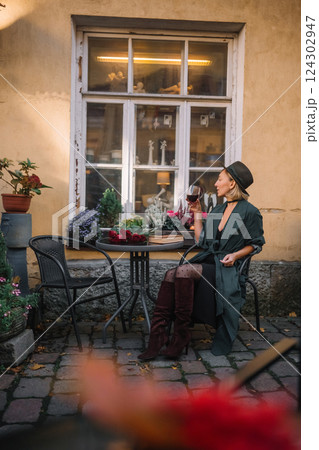 Stylish woman enjoying a drink at an outdoor cafe in a historic setting during sunset Stylish woman enjoying a drink at an outdoor cafe in a historic setting during sunset 124302947