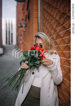 Woman enjoys fragrant roses in an urban setting on a sunny day 124302968