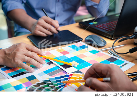 Interior designer chooses a color chart for home design. Graphic designers working on color chart at modern office. Interior designer chooses a color chart for home design. Graphic designers working on color chart at modern office. 124303921