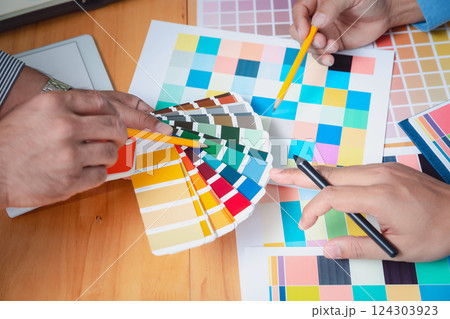 Interior designer chooses a color chart for home design. Graphic designers working on color chart at modern office. Interior designer chooses a color chart for home design. Graphic designers working on color chart at modern office. 124303923