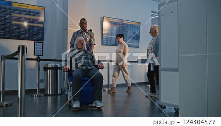 Airport Terminal: Senior Man Getting Up from Wheelchair, Walking Through Metal Detector Scanning Gates Airport Terminal: Senior Man Getting Up from Wheelchair, Walking Through Metal Detector Scanning Gates 124304577