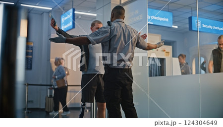 TSA Officer Checking Young Man with Prosthetic Leg in Airport Terminal 124304649