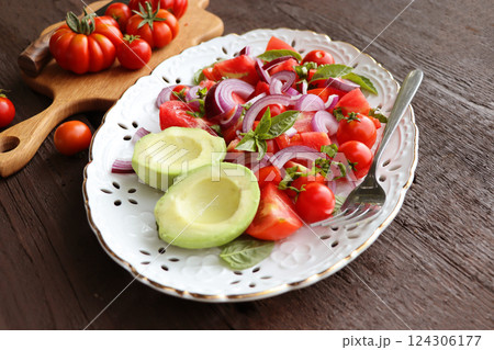 Fresh healthy avocado and tomato salad with onions on dark rustic background . Fresh healthy avocado and tomato salad with onions on dark rustic background . 124306177