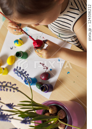 Little child girl paint Easter eggs at home. kid is preparing for Easter. Little child girl paint Easter eggs at home. kid is preparing for Easter. 124306212