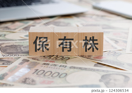 お金の上に保有株と書かれたブロック 124306534