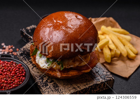 Delicious burger with beef patty, fried egg, bacon, herbs, sauce, salt and spices Delicious burger with beef patty, fried egg, bacon, herbs, sauce, salt and spices 124306559