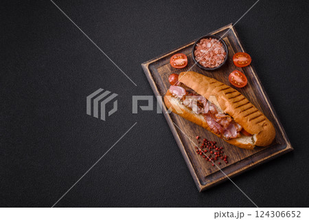 Delicious juicy hot dog with sausage, bacon, sauce, salt and spices Delicious juicy hot dog with sausage, bacon, sauce, salt and spices 124306652