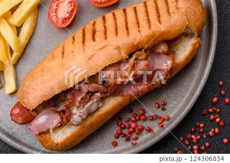 Delicious juicy hot dog with sausage, bacon, sauce, salt and spices Delicious juicy hot dog with sausage, bacon, sauce, salt and spices 124306834