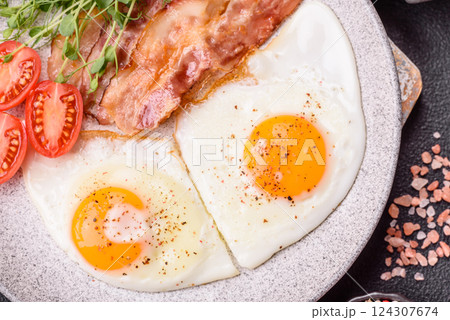 A hearty breakfast with fried eggs, bacon, tomatoes, microgreens 124307674