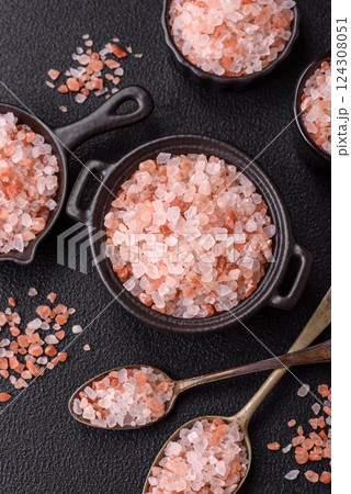Pink himalayan salt in a black bowl on a dark concrete background 124308051