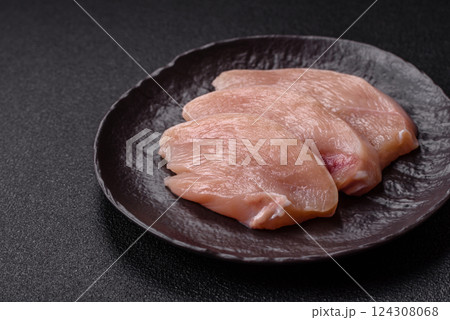 Fresh chicken fillet on a dark concrete table with spices and herbs Fresh chicken fillet on a dark concrete table with spices and herbs 124308068