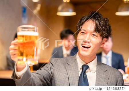 居酒屋でビールの乾杯をするサラリーマンの男性 124308274