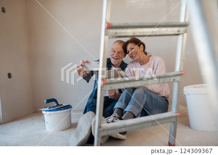 Senior couple taking break during their home renovation, taking a selfie. 124309367