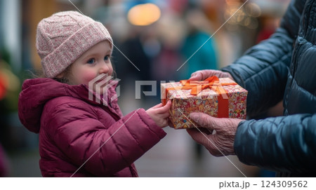 A young girl happily receiving a beautifully wrapped gift. The exchange captures a moment of joy and excitement. This scene is perfect for festive themes. Generative AI 124309562