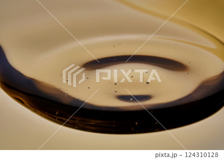 Texture of pouring cosmetic oil on a golden background. 124310128