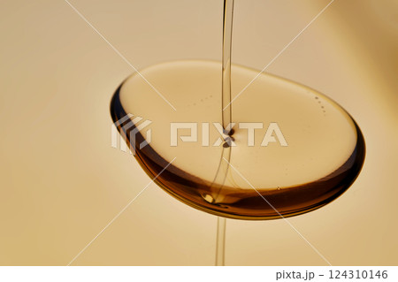 Texture of pouring cosmetic oil on a golden background. 124310146
