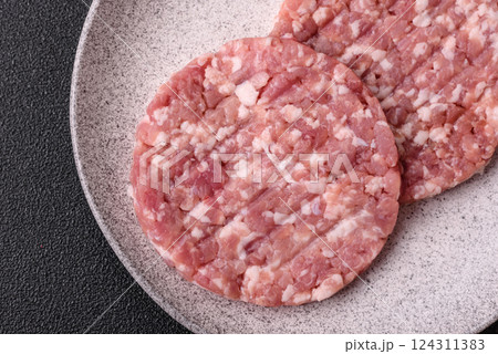 Fresh raw ground beef or pork burger patty with salt and spices 124311383