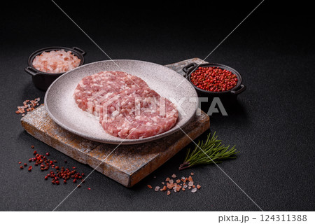 Fresh raw ground beef or pork burger patty with salt and spices Fresh raw ground beef or pork burger patty with salt and spices 124311388