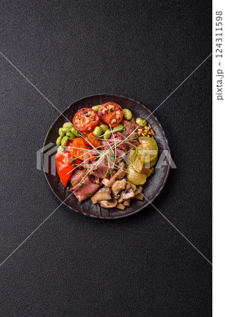 Warm salad consisting of slices of roast beef, greens, tomatoes, cucumbers, green beans 124311598