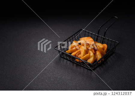 Baked potato wedges with cheese and herbs on a dark background Baked potato wedges with cheese and herbs on a dark background 124312037
