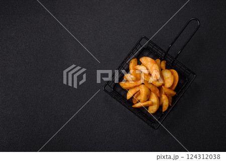 Baked potato wedges with cheese and herbs on a dark background Baked potato wedges with cheese and herbs on a dark background 124312038