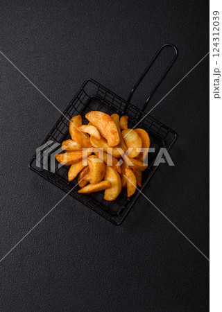 Baked potato wedges with cheese and herbs on a dark background Baked potato wedges with cheese and herbs on a dark background 124312039