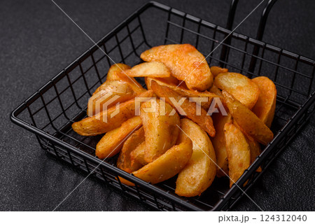 Baked potato wedges with cheese and herbs on a dark background Baked potato wedges with cheese and herbs on a dark background 124312040
