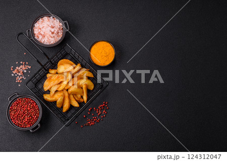 Baked potato wedges with cheese and herbs on a dark background Baked potato wedges with cheese and herbs on a dark background 124312047