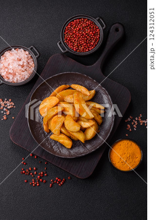 Baked potato wedges with cheese and herbs on a dark background Baked potato wedges with cheese and herbs on a dark background 124312051