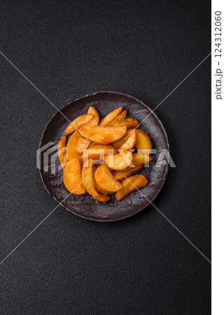 Baked potato wedges with cheese and herbs on a dark background Baked potato wedges with cheese and herbs on a dark background 124312060