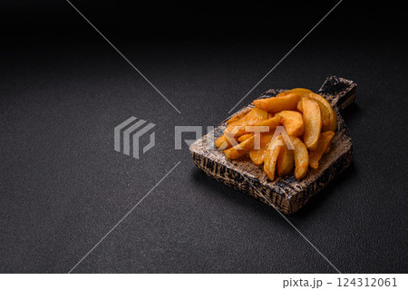 Baked potato wedges with cheese and herbs on a dark background Baked potato wedges with cheese and herbs on a dark background 124312061